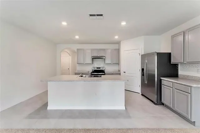 a kitchen with stainless steel appliances granite countertop a refrigerator a sink a stove a microwave and white cabinets