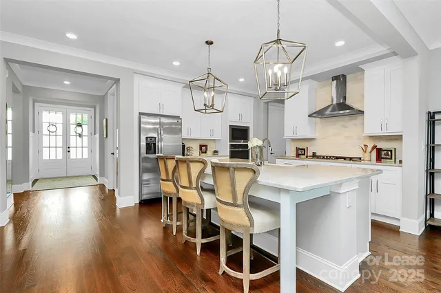 a kitchen with stainless steel appliances kitchen island granite countertop a table chairs in it and wooden floors