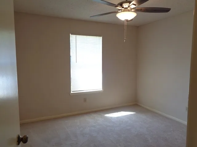 an empty room with a window and a fan