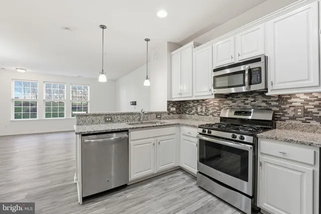 a kitchen with stainless steel appliances granite countertop a stove a sink and a microwave