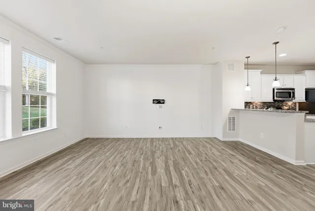a view of a kitchen with wooden floor and white cabinets