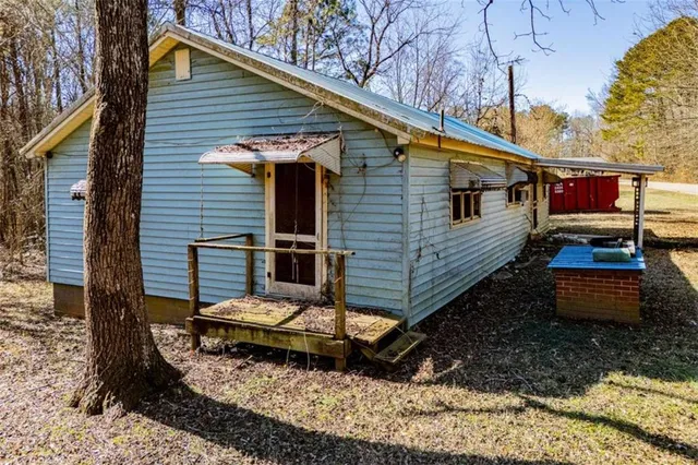 a view of a small house with yard and wooden fence
