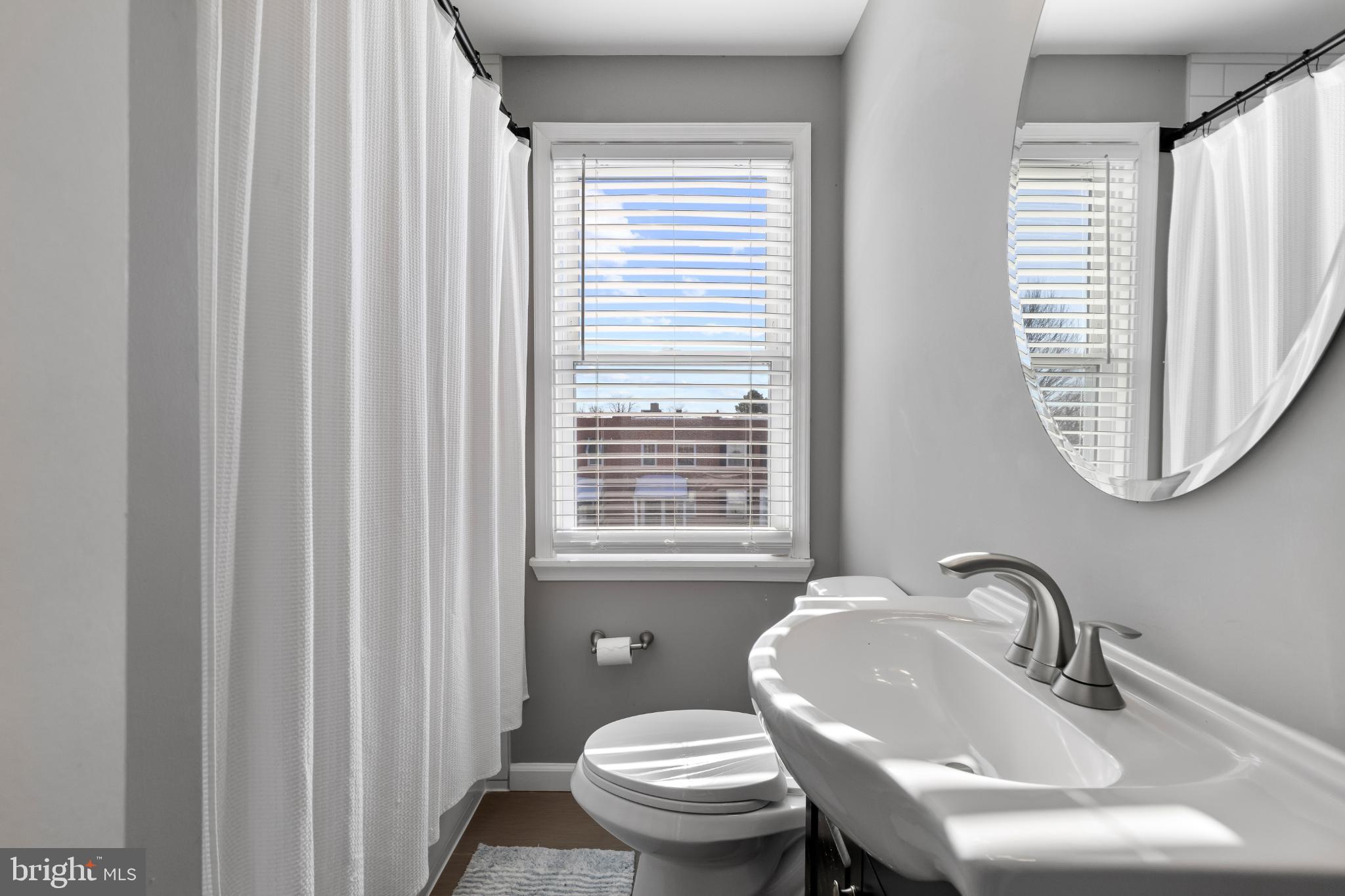1002 West 43rd Street Baltimore, MD 21211 - Photo 16 of 23 a bathroom with a sink a toilet and a mirror
