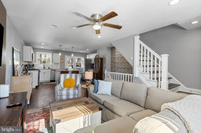 a living room with furniture kitchen view and a chandelier