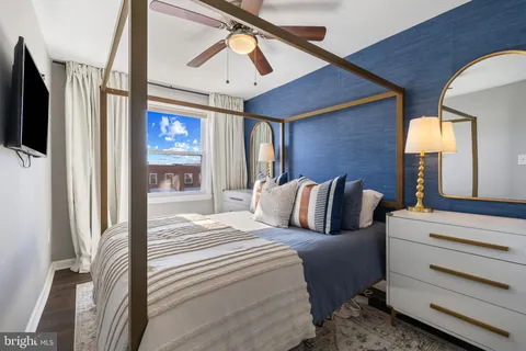 a bedroom with a bed a flat screen tv and a large window