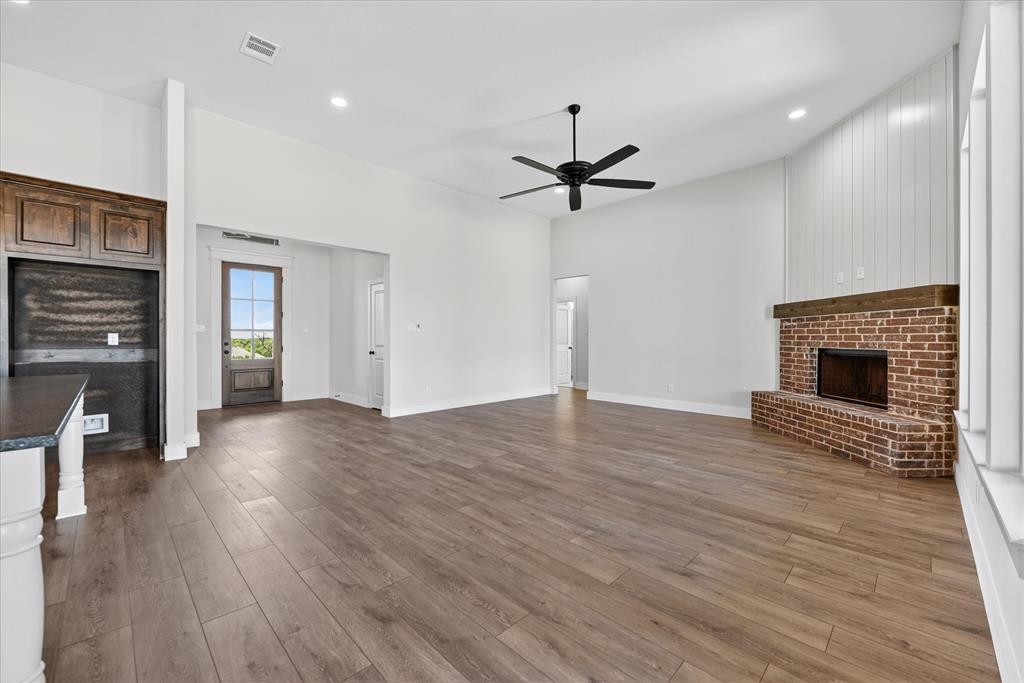 517 Longhorn Lane Springtown, TX 76082 - Photo 8 of 39 Unfurnished living room featuring a fireplace, dark wood finished floors, ceiling fan, recessed lighting, and a high ceiling