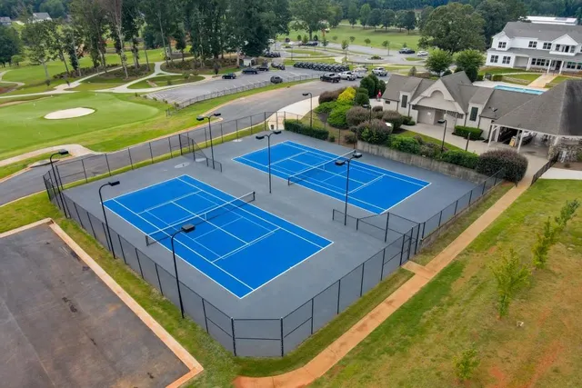 a view of a tennis court with a swimming pool and outdoor seating