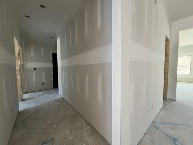 a view of a hallway with wooden floor and a bathroom
