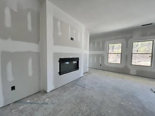 an empty room with windows and fireplace