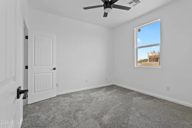 an empty room with a window and a fan
