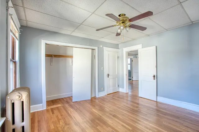 a view of empty room with wooden floor and ceiling fan