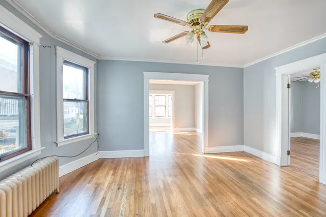 a view of an empty room with window and wooden floor