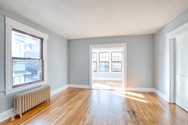 a view of an empty room with wooden floor and a window