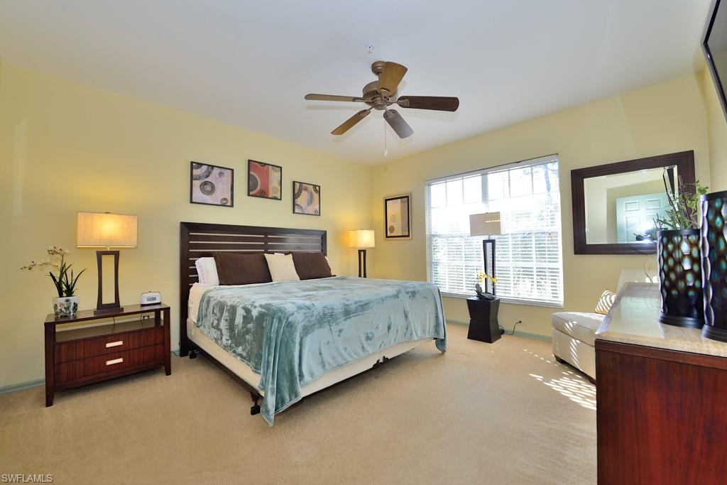 8125 Celeste Drive, Unit 5216 Naples, FL 34113 - Photo 7 of 11 a spacious bedroom with a bed a couch and a chandelier