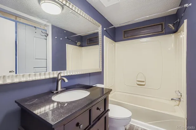 a bathroom with a granite countertop sink toilet and shower