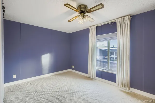 an empty room with windows and fan