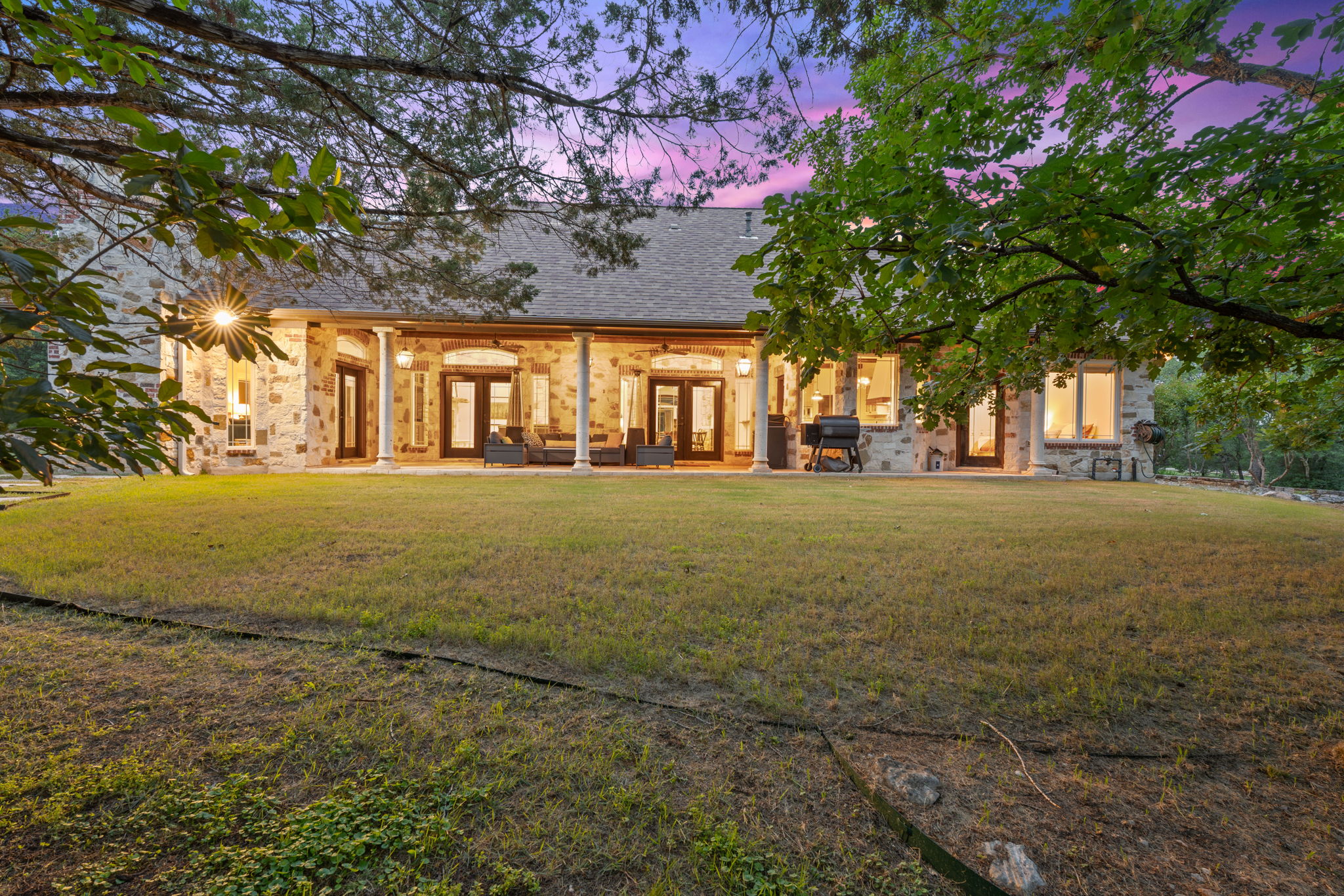 8121 Bluff Trail Austin, TX 78737 - Photo 31 of 40 A gracious stone facade with covered patio and mature trees defines this property's rear exterior.