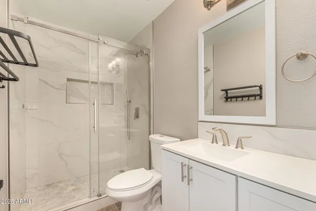 a bathroom with a granite countertop sink toilet a mirror and shower