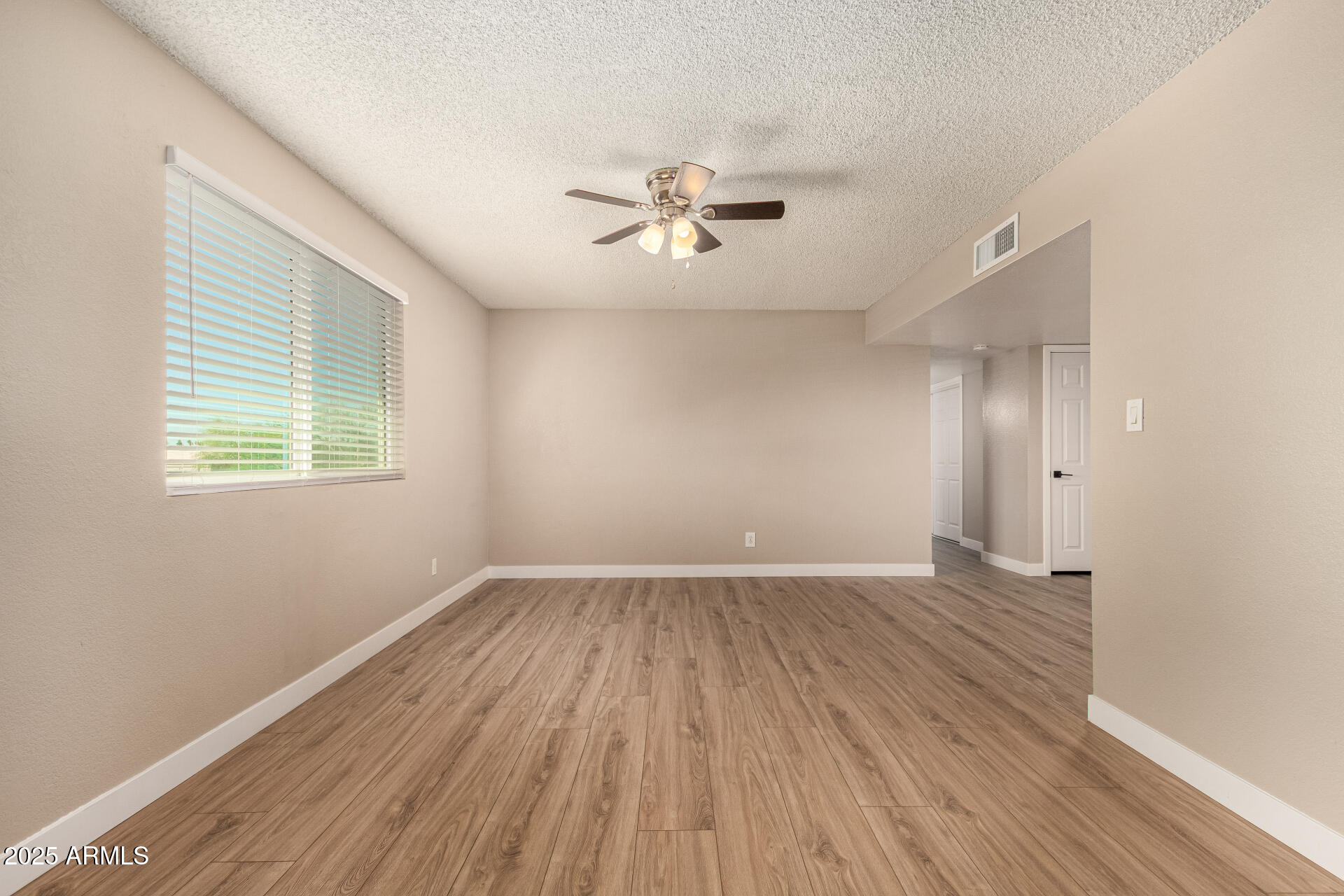 2633 West Ocotillo Road, Unit 3 Phoenix, AZ 85017 - Photo 5 of 27 an empty room with wooden floor ceiling fan and windows