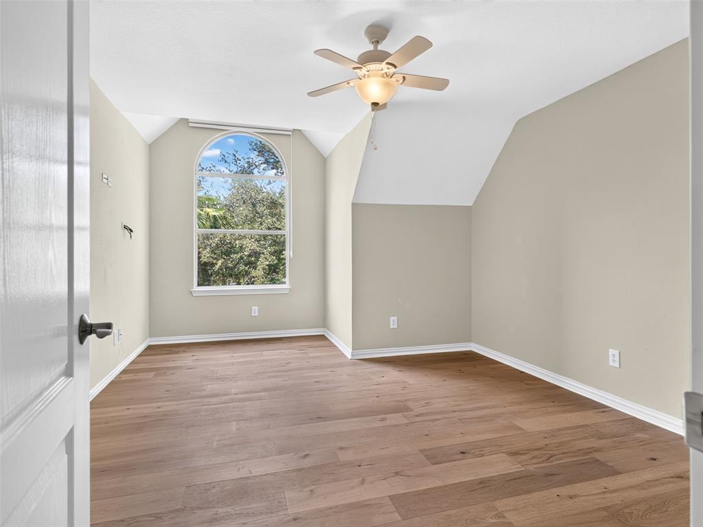 6809 Cedar Ridge Court Plano, TX 75093 - Photo 28 of 38 Wood-finish flooring, vaulted ceiling, arched window, and a ceiling fan with light fixture