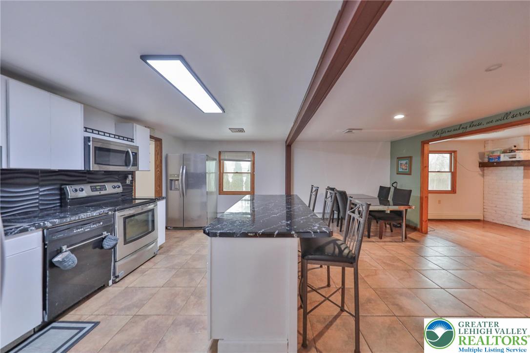 257 Hoffman Road Wind Gap, PA 18091 - Photo 29 of 52 a kitchen with stainless steel appliances granite countertop a stove top oven a sink a dining table and chairs