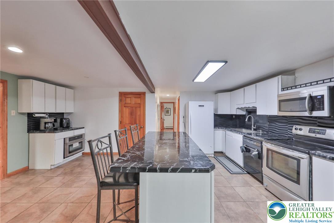 257 Hoffman Road Wind Gap, PA 18091 - Photo 31 of 52 a kitchen with kitchen island granite countertop a stove top oven microwave and cabinets