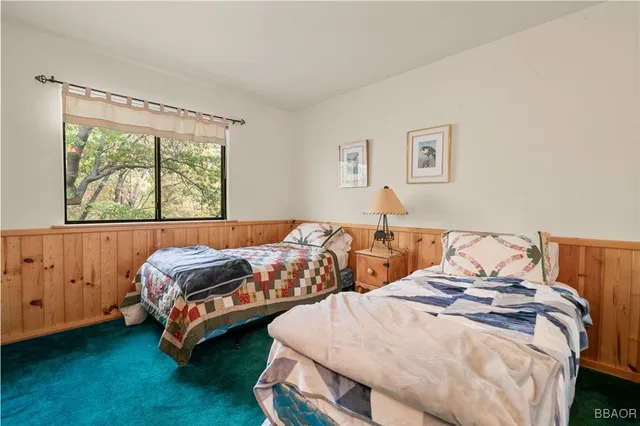 a bedroom with two beds and a dresser next to a window