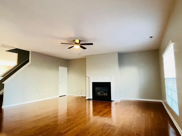 an empty room with wooden floor fireplace and windows