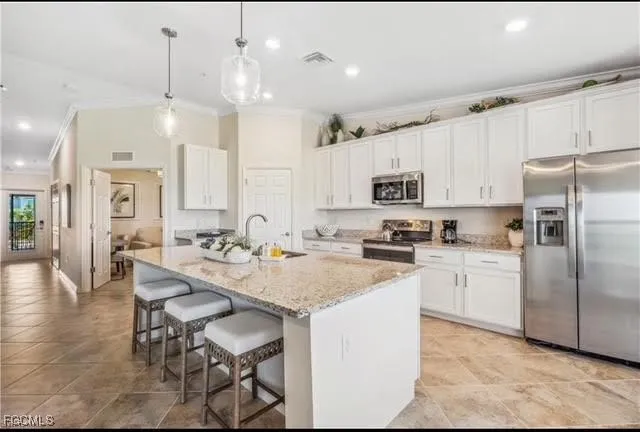 a kitchen with granite countertop a refrigerator a stove a sink a dining table and chairs