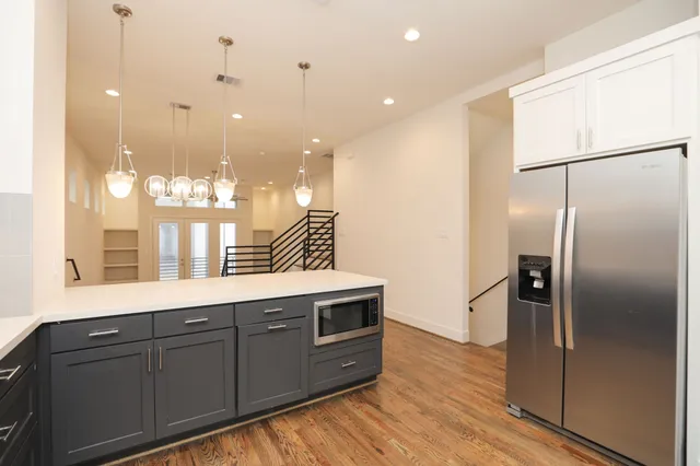 a kitchen with stainless steel appliances granite countertop a refrigerator a oven and a sink with wooden floor