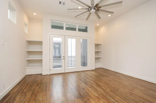 an empty room with wooden floor closet and windows