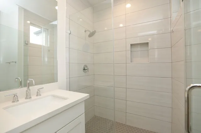 a bathroom with a sink shower and a mirror