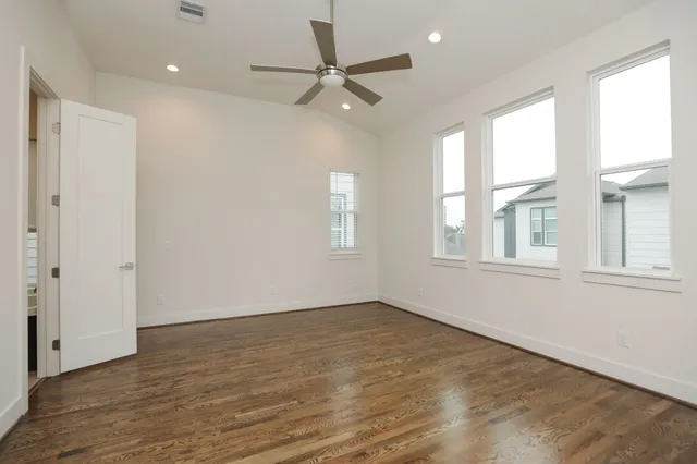 a view of an empty room with a window and wooden floor