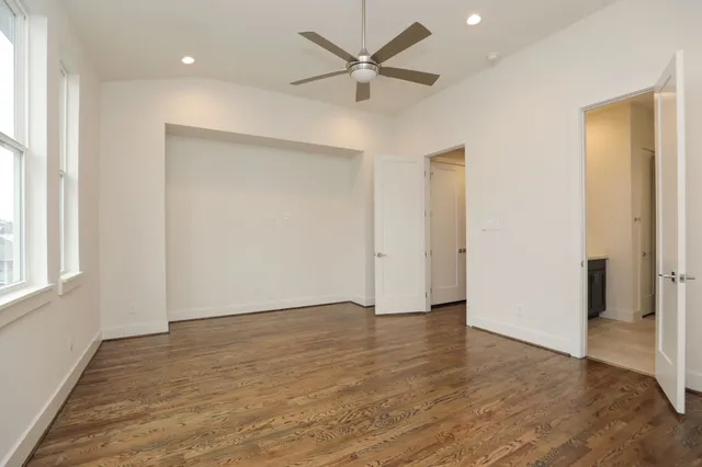 an empty room with wooden floor and a ceiling fan