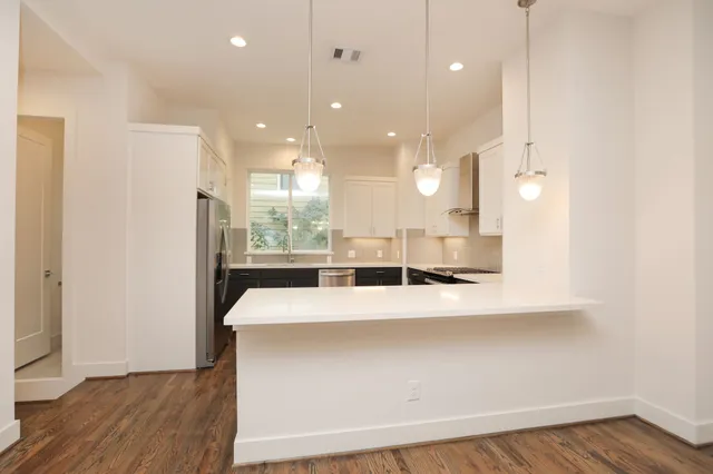 a large white kitchen with a large island oven a stove with kitchen island