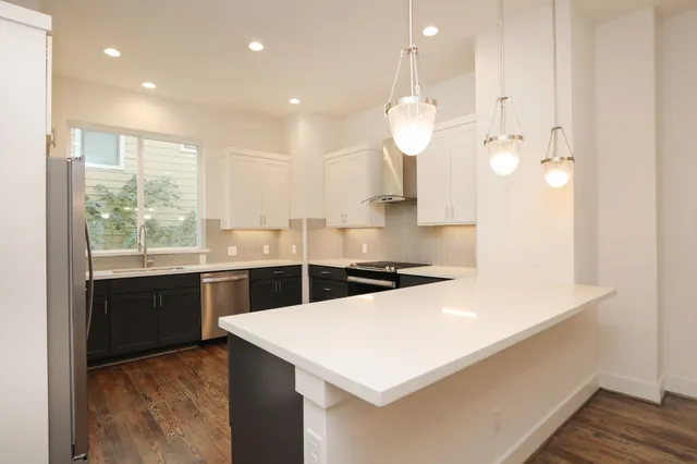 a kitchen with a refrigerator a sink and dishwasher with wooden floor