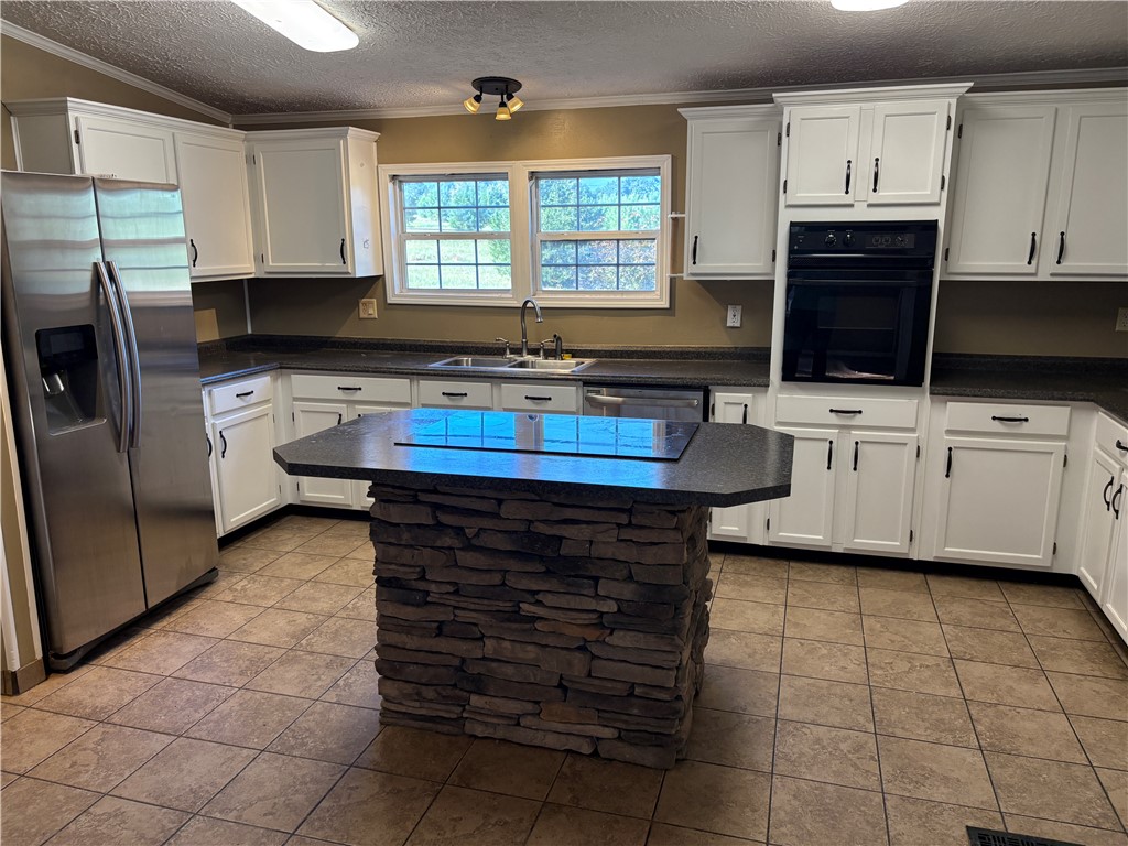1108 Trotter Road Anderson, SC 29626 - Photo 2 of 27 A stone-wrapped center island anchors this functional kitchen featuring white cabinetry and tile flooring.