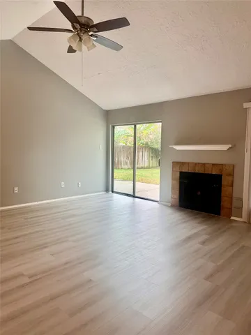 an empty room with windows fireplace and a ceiling fan