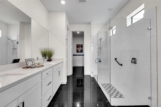 a bathroom with a double vanity sink a large mirror a shower and vanity