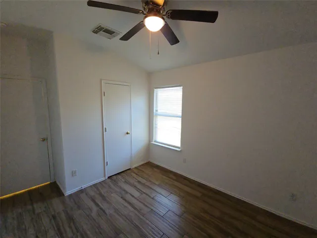 a view of empty room with wooden floor and fan