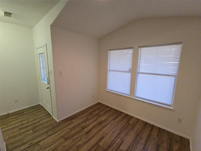 a view of an empty room with wooden floor and a window