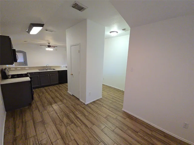 a large kitchen with wooden floor and stainless steel appliances