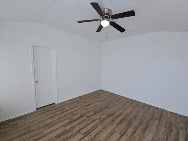 an empty room with wooden floor and a ceiling fan