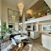 a living room with furniture a chandelier and kitchen view