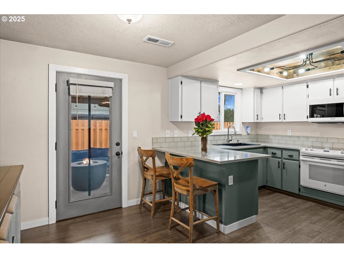 2788 South Beech Street Cornelius, OR 97113 - Photo 13 of 40 a kitchen with stainless steel appliances granite countertop a stove top oven a sink dishwasher and white cabinets with wooden floor