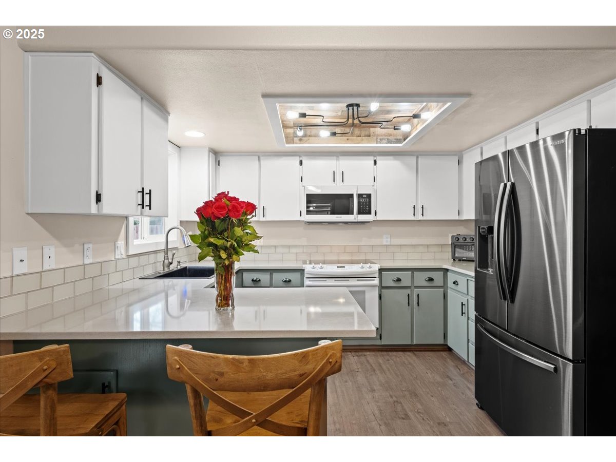 2788 South Beech Street Cornelius, OR 97113 - Photo 14 of 40 a kitchen with stainless steel appliances granite countertop a refrigerator a sink dishwasher and white cabinets with wooden floor