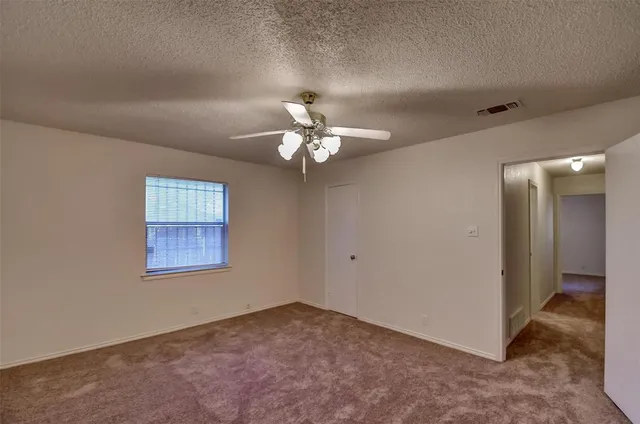 an empty room with a chandelier fan and windows
