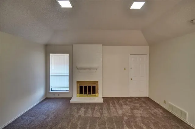 a view of an empty room with window and fireplace
