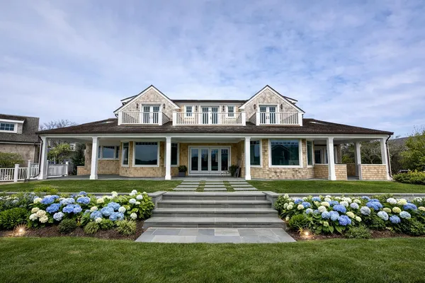 a front view of a house with a garden and trees