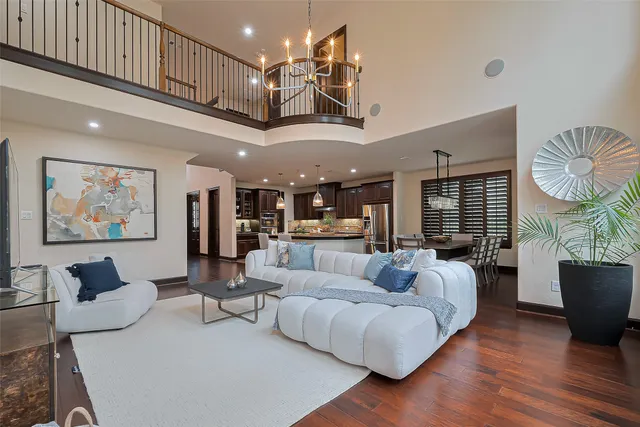 a living room with furniture kitchen view and a chandelier